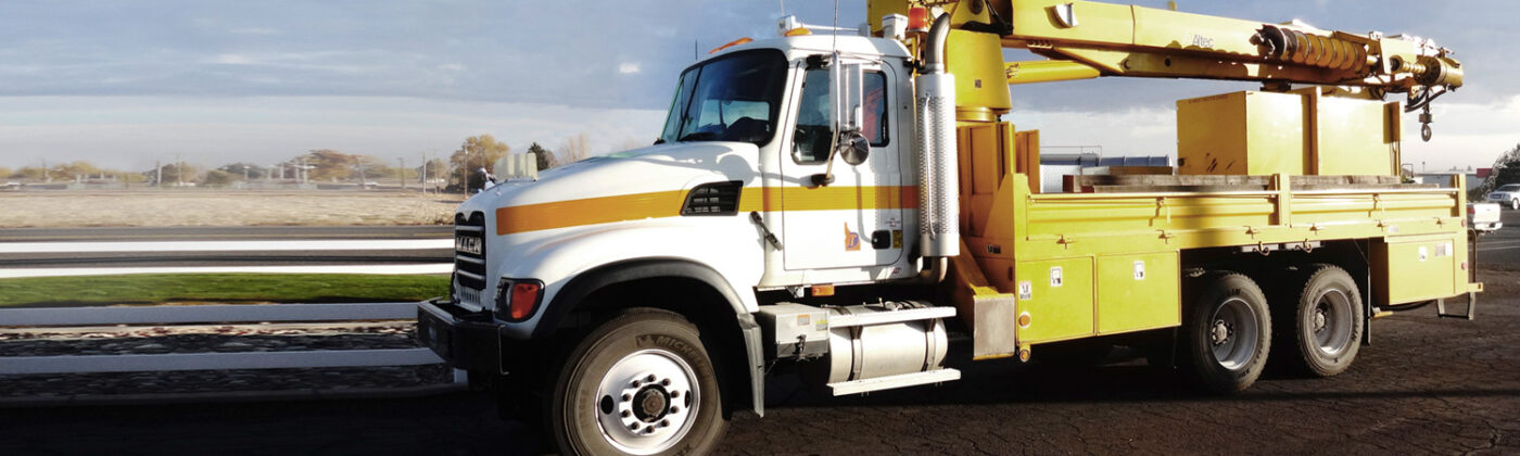 A boom mounted truck parked by a field