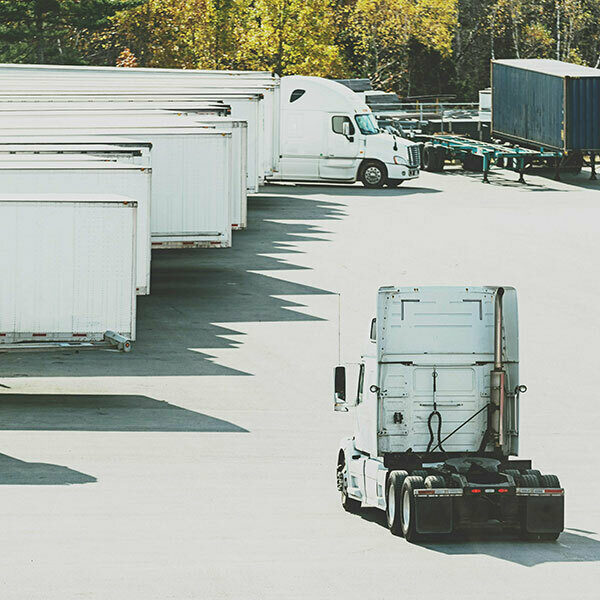 A semi cab driving down a lane with several trailers