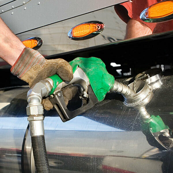A hand filling a a semi truck's gas tank