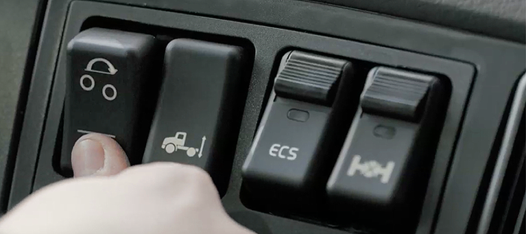 Finger pressing the lift axle lower button on a 6x2 system.