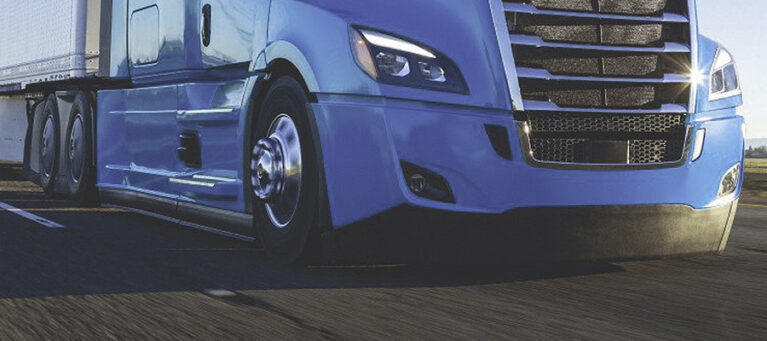 A blue semi truck hauling a trailer on a highway