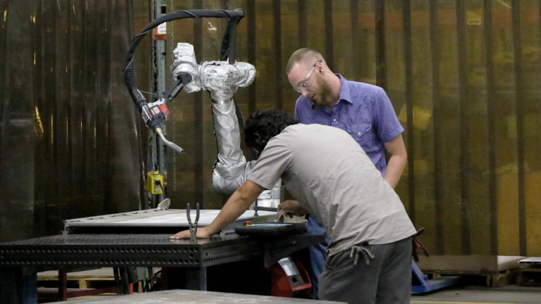 Two men working together to program cobot