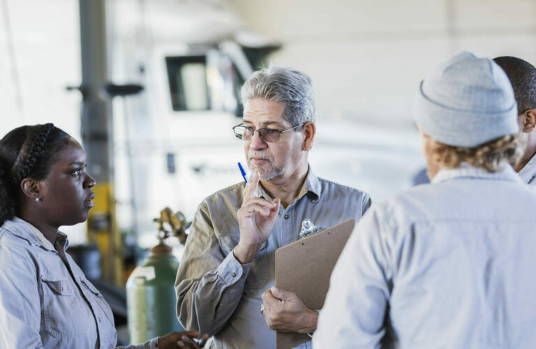 Man with clipboard in discussion with 3 people