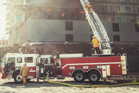 Fire fighters on and near a ladder fire truck with the ladder extended