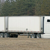 A white semi truck hauling two trailers