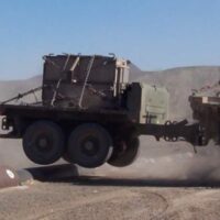 A military trailer being towed over a bump in the road