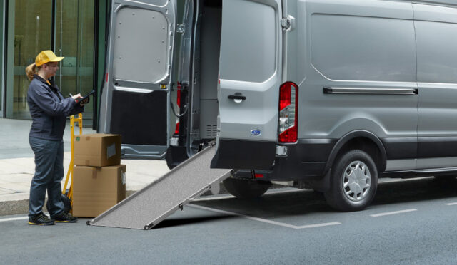 A woman preparing to dolly boxes into a cargo van