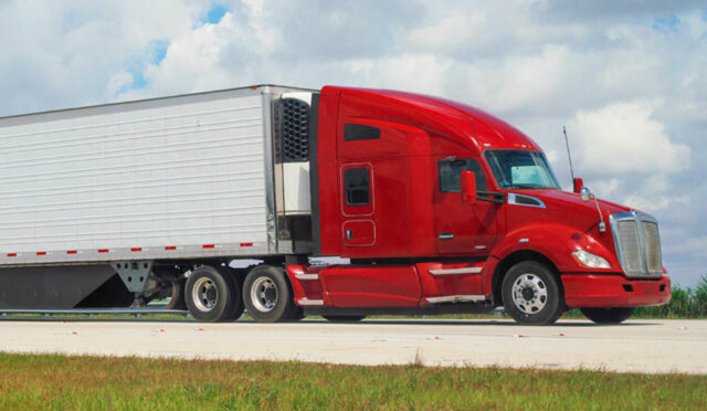 Red semi truck hauling an enclosed trailer on a highway