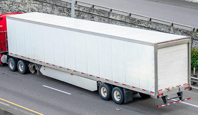 A red truck hauling an enclosed trailer on a highway