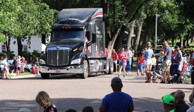 Link employees walking with the Link semi truck cab in a parade