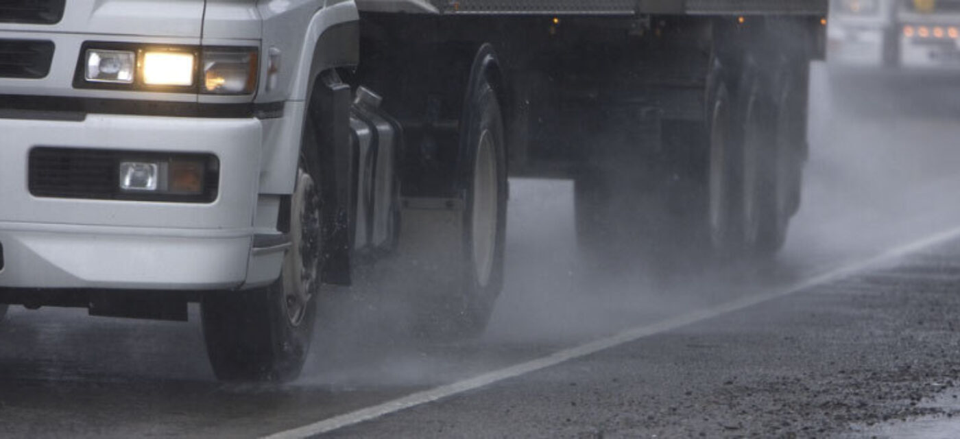 A photo of a semi truck's tires on a road in the rain