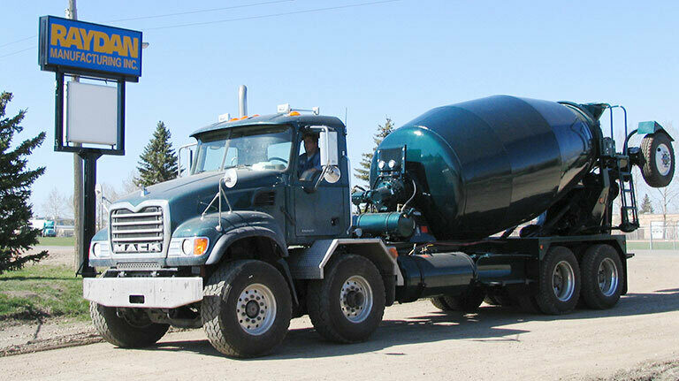 Blue Mack cement mixer parked in front of a Raydan Manufacturing Inc. sign