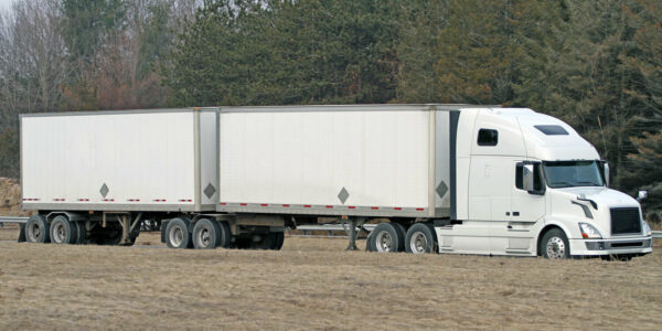 A white semi truck hauling two trailers