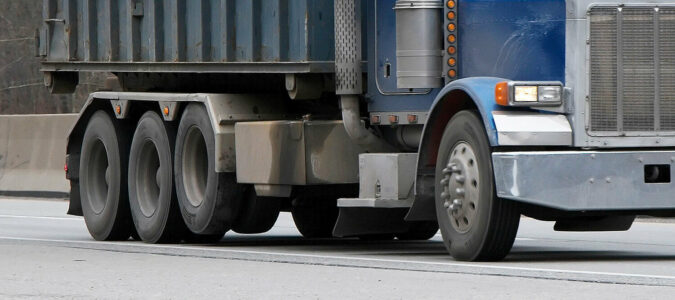 Tires on a dump truck, including a lifted non-steerable auxiliary suspension