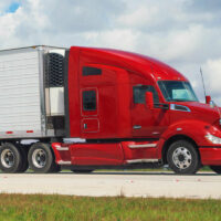 Red semi truck hauling an enclosed trailer on a highway